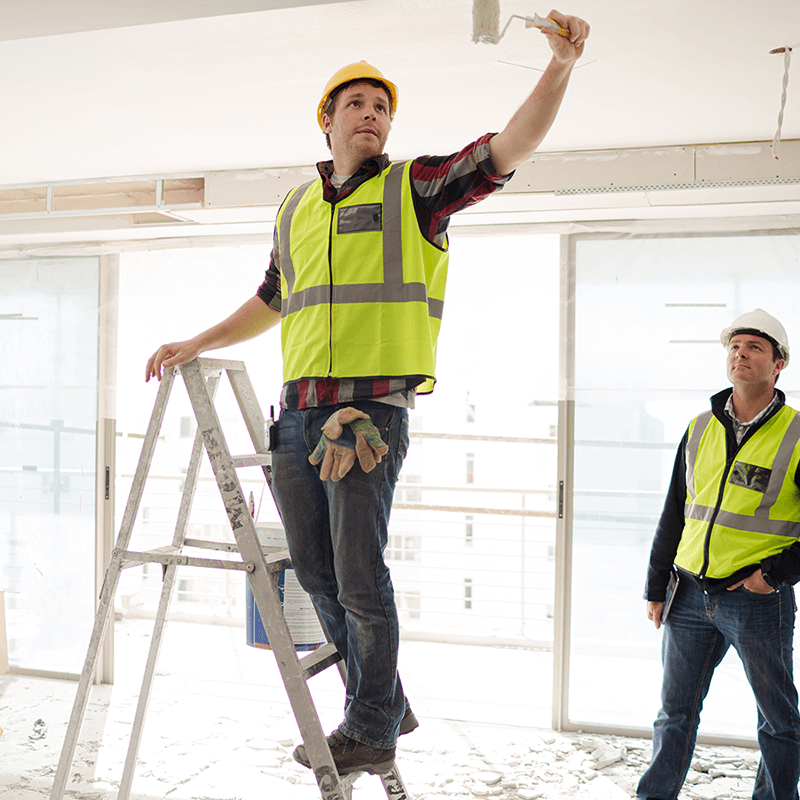 commercial painter working in an office remodel project painting the ceiling and molding