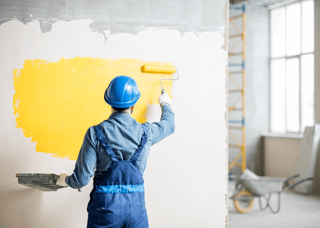 painter painting an interior wall yellow on a commercial painting project